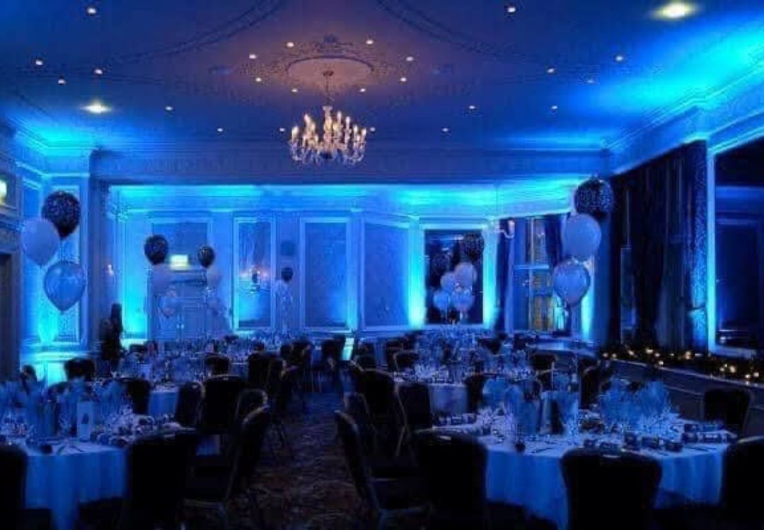 Wedding reception room with blue uplighting, chandeliers and decorated tables