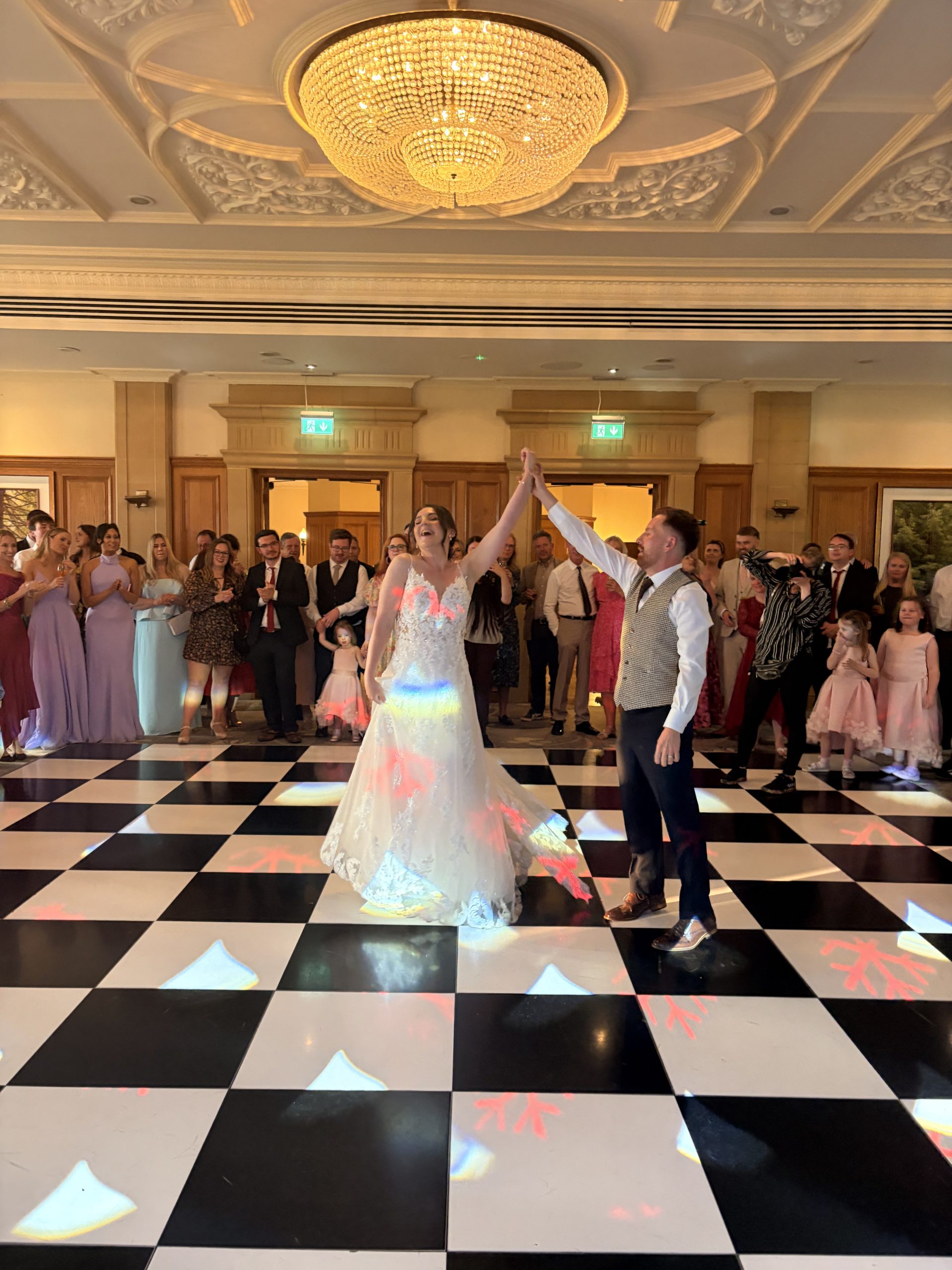 sdc-hero Bride and groom celebrating on a black and white dance floor with guests at a Sussex wedding